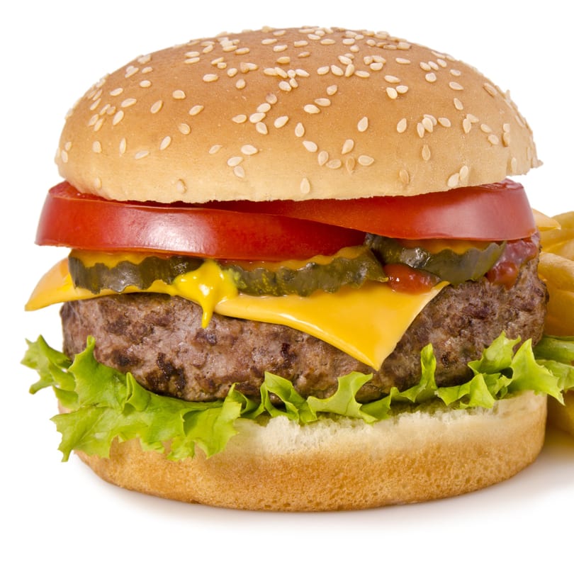 A juicy cheeseburger with lettuce, tomato, pickles, and ketchup, served with fries.
